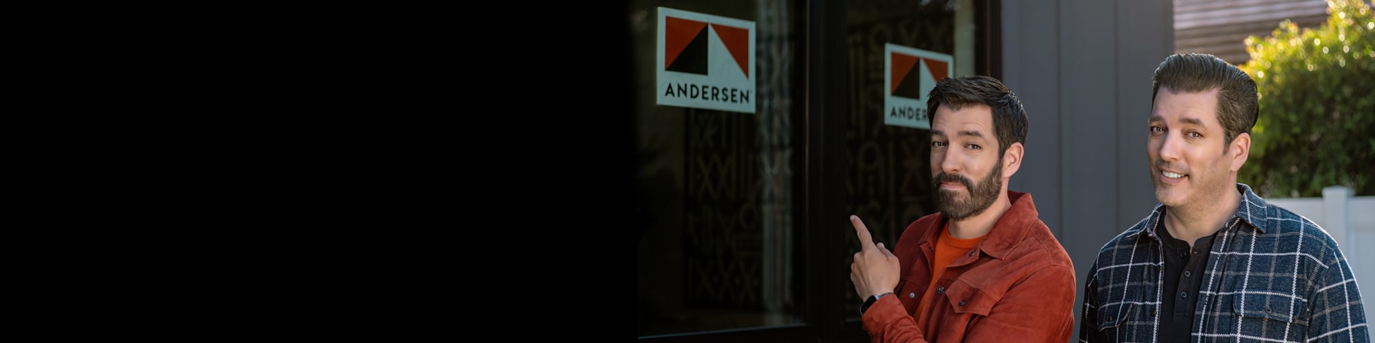 Drew and Jonathan Scott standing in front of new home with Andersen Windows stickers on the windows